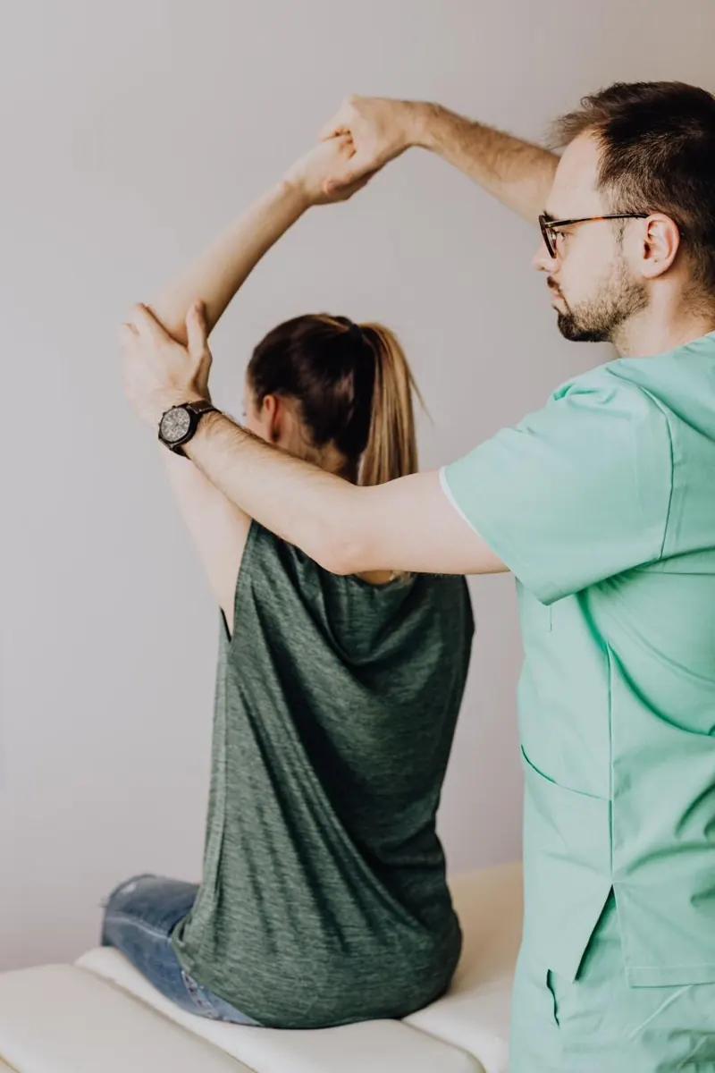 Kinesiólogo guiando la elongación del brazo de una paciente